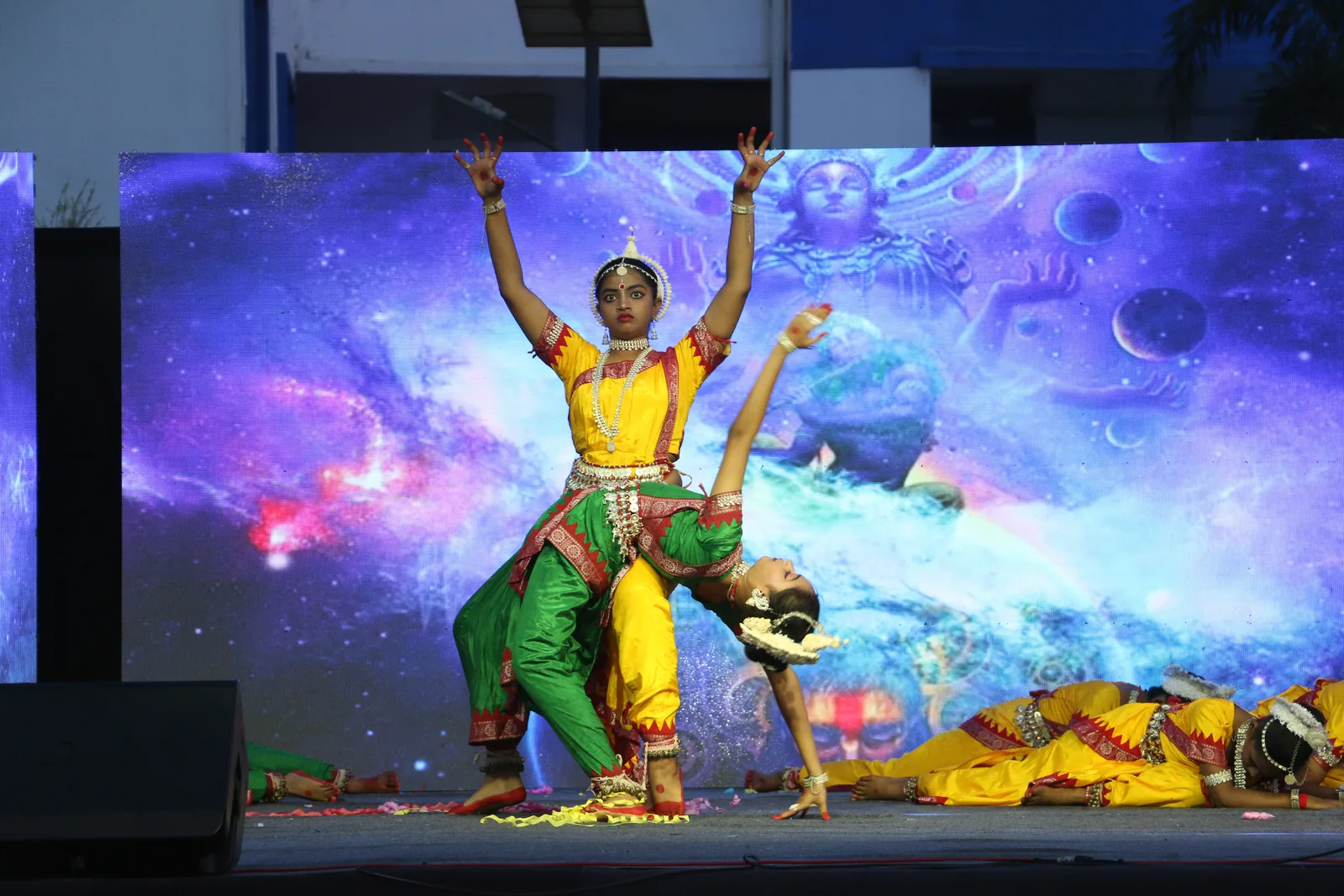 Solo classical Odissi dancer performing on outdoor floodlit stage.