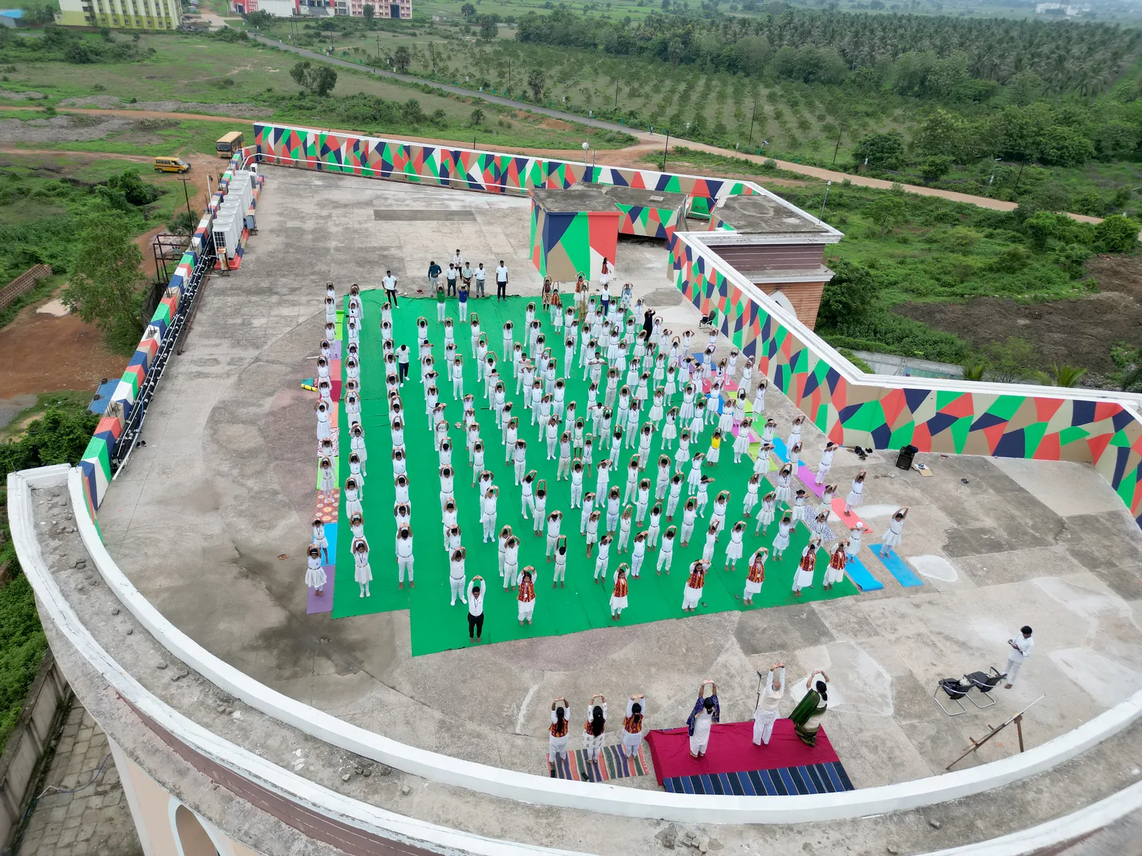 Aerial drone perspective of hundreds of students performing synchronized yoga asanas.