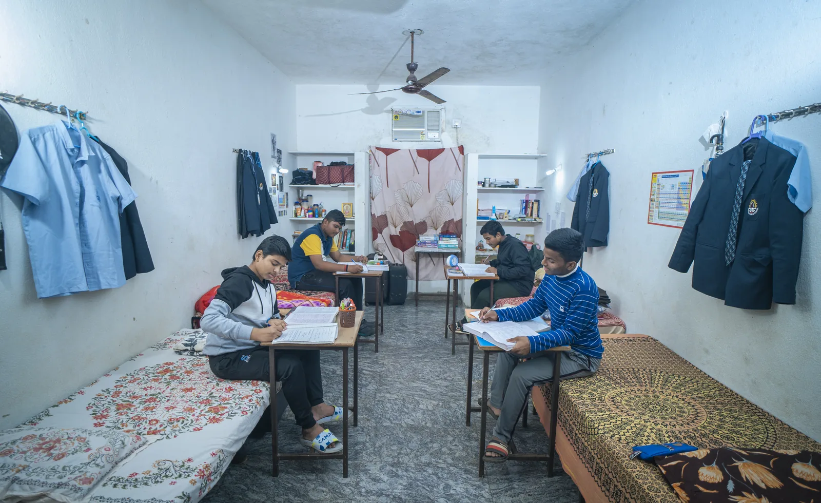 Two boys studying at desks in their comfortable hostel room.
