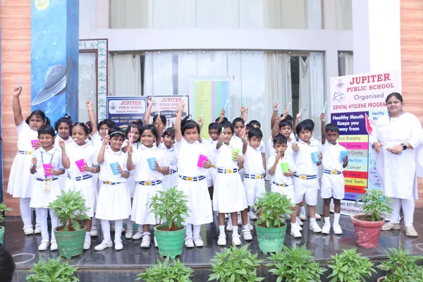 Students at a school dental hygiene programme holding toothbrushes.