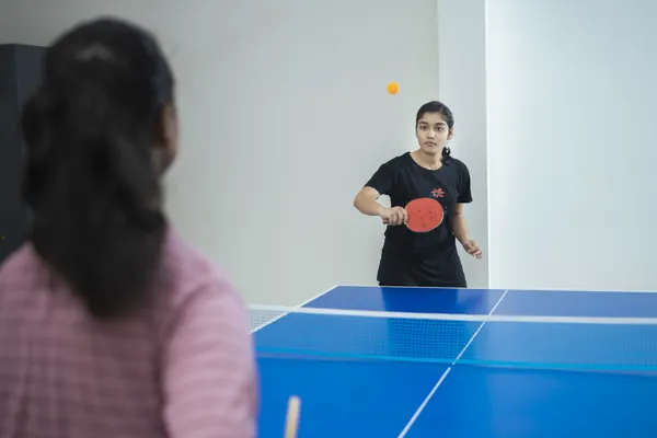 Student playing a competitive indoor table tennis match.